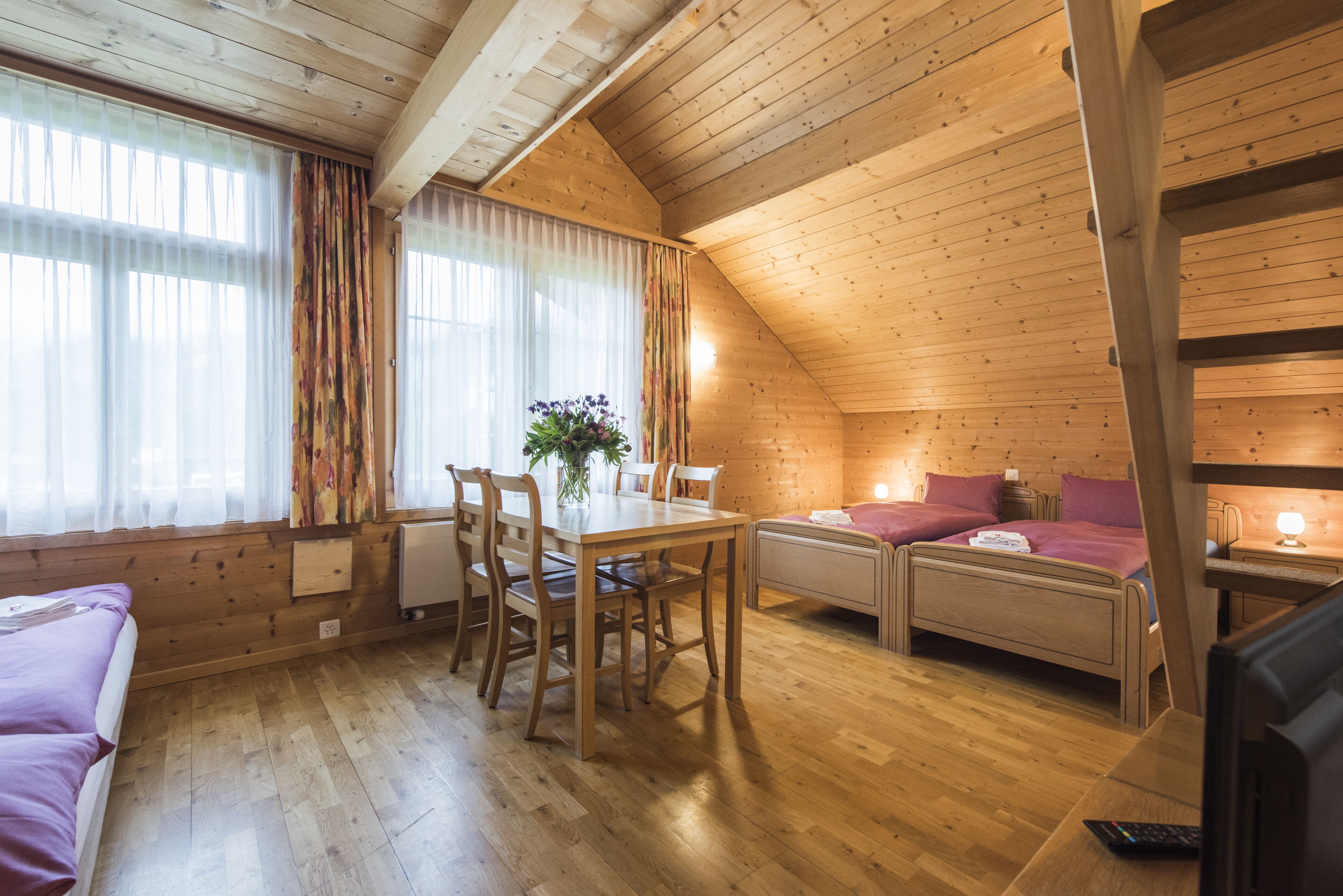 Ein gemütliches Blockhaus mit Holzvertäfelung, einem Essbereich, einem Bett und einem Fernseher.