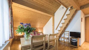 Un interior de madera con una mesa de comedor, sillas, un televisor y una escalera.