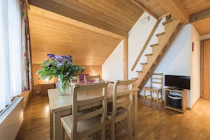Un interior de madera con una mesa de comedor, sillas, un televisor y una escalera.