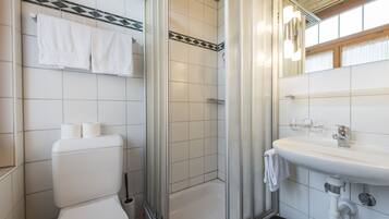 A bathroom with a toilet, shower, and sink.