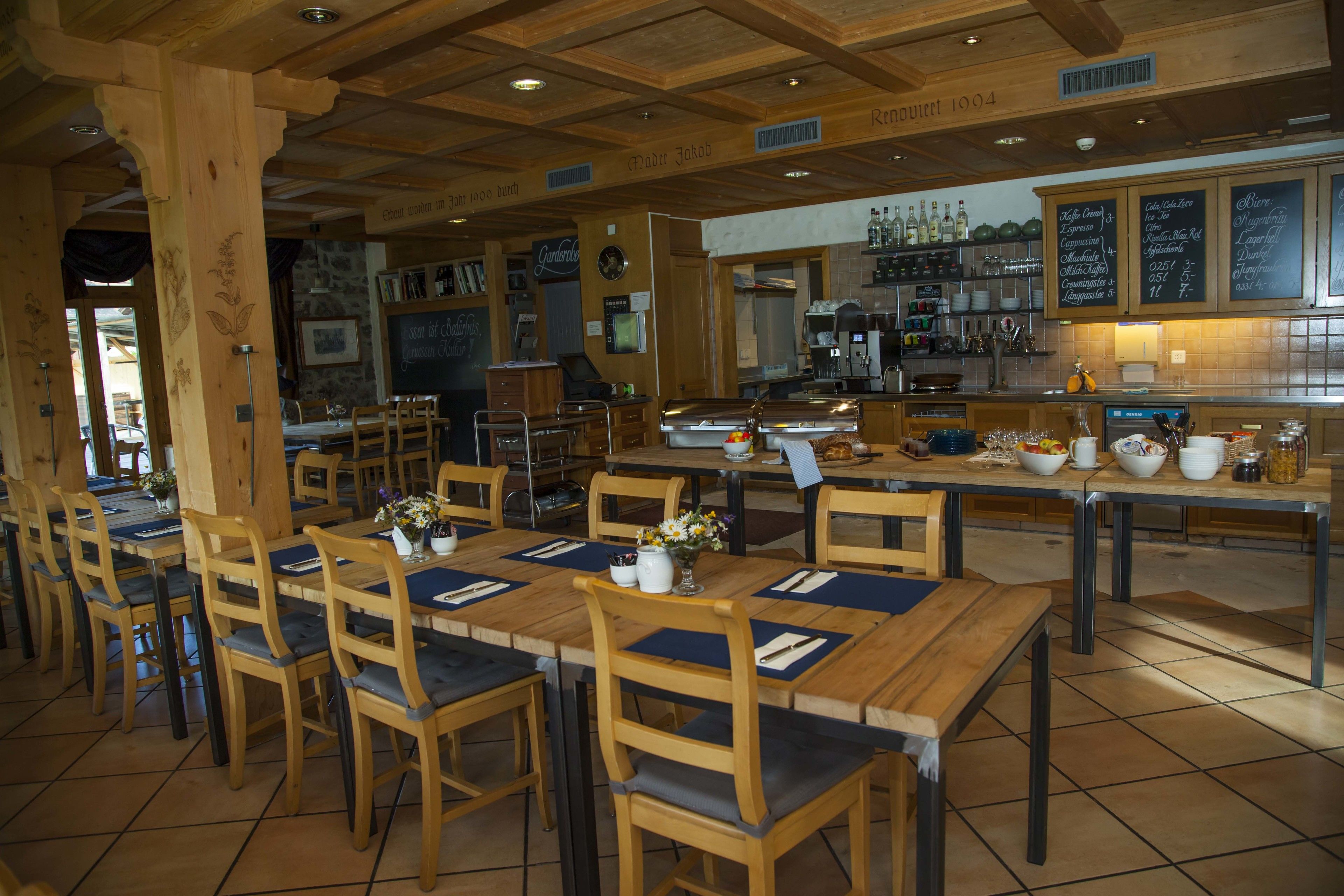 Un restaurante con mesas y sillas de madera, una zona de bar y un panel con la carta.