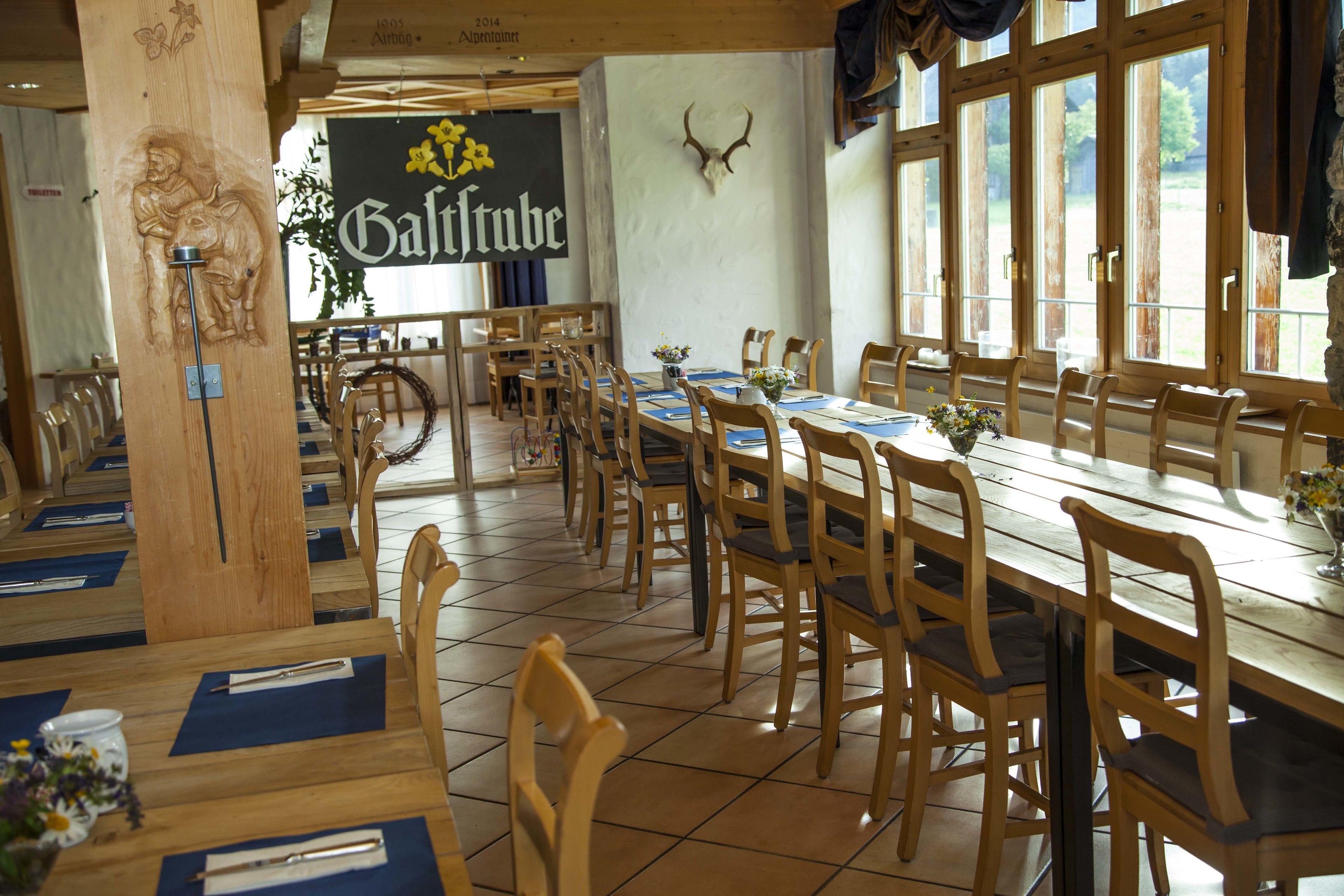 A restaurant with wooden tables and chairs, a large antler on the wall, and a sign reading "Galtube".