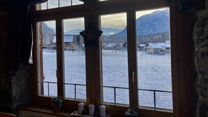 Una habitación con un ventanal grande que da a un paisaje nevado y montañas.
