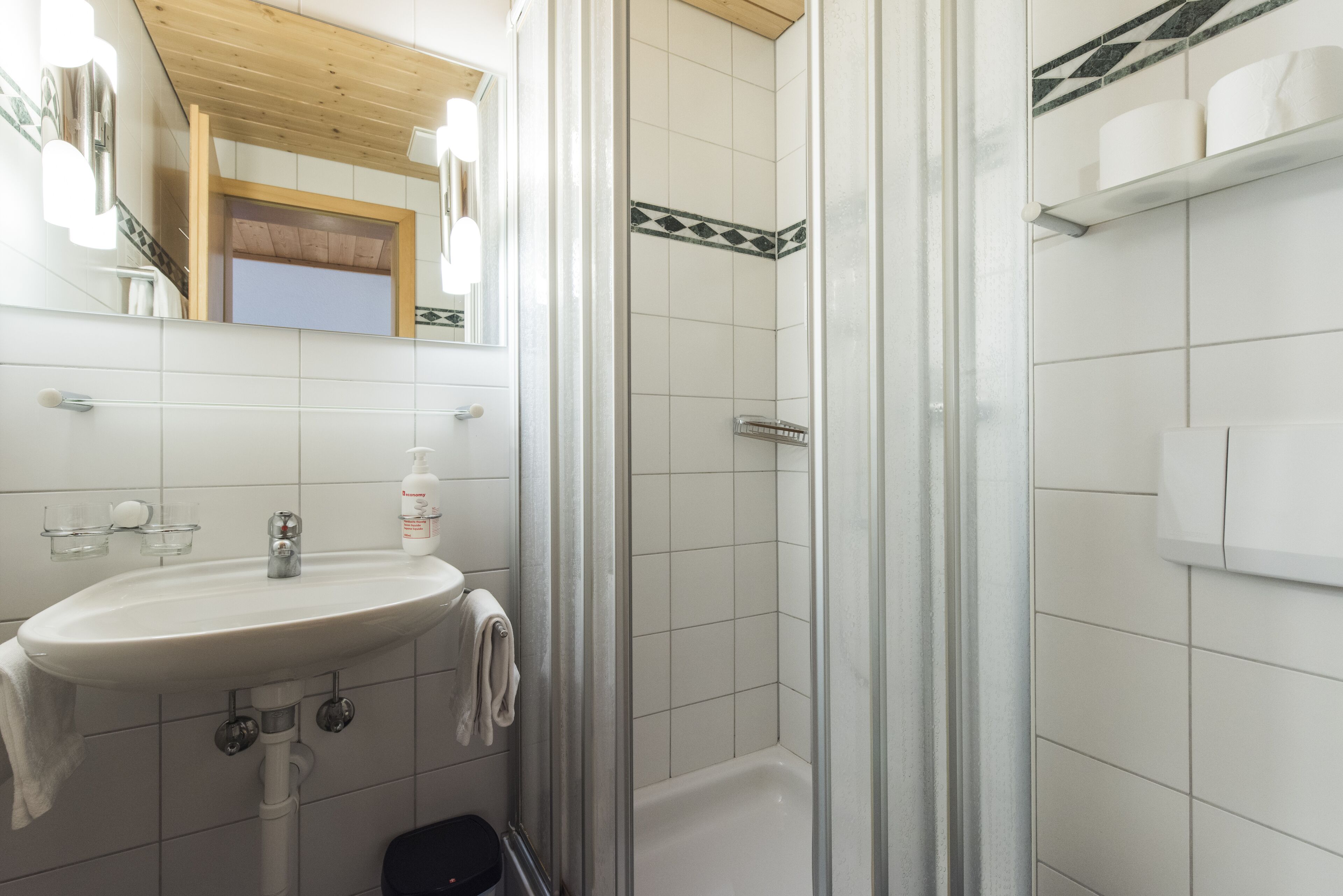 Un baño con lavamanos, espejo, ducha e inodoro.