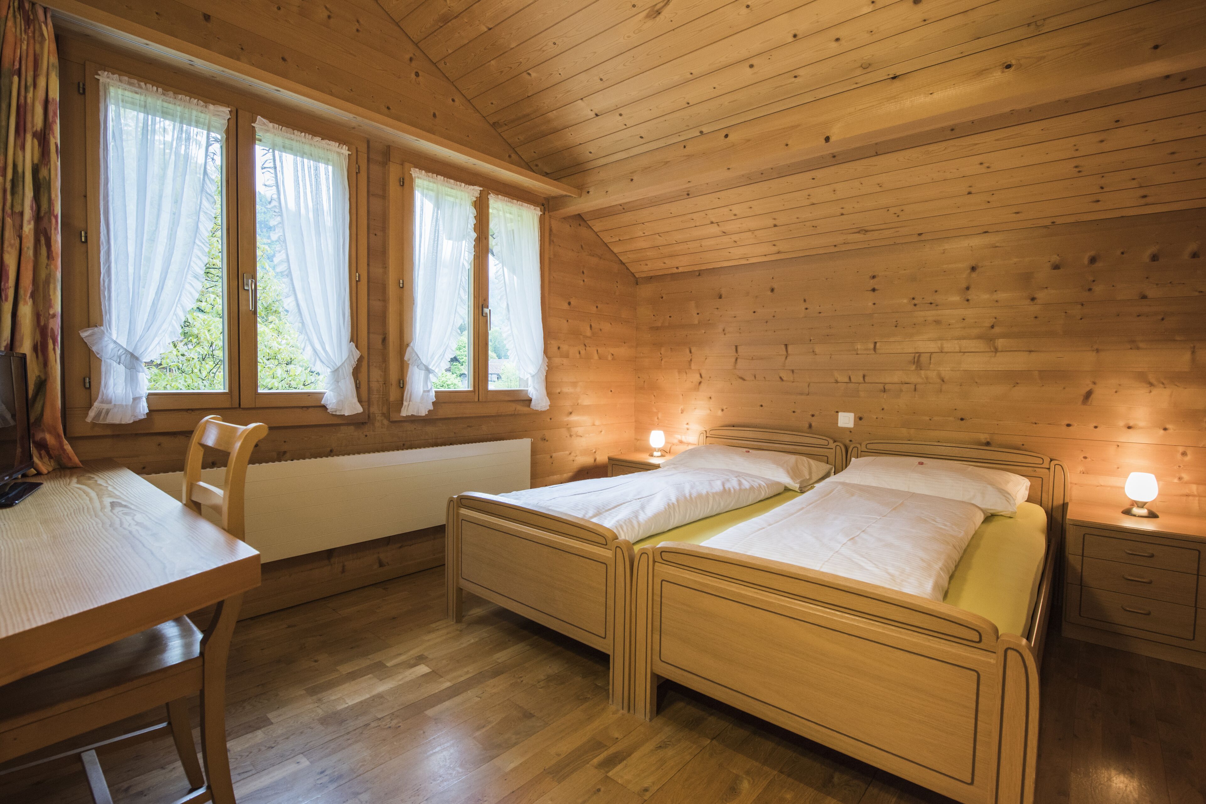 Una habitación de cabaña de madera con dos camas, una mesa y una silla.