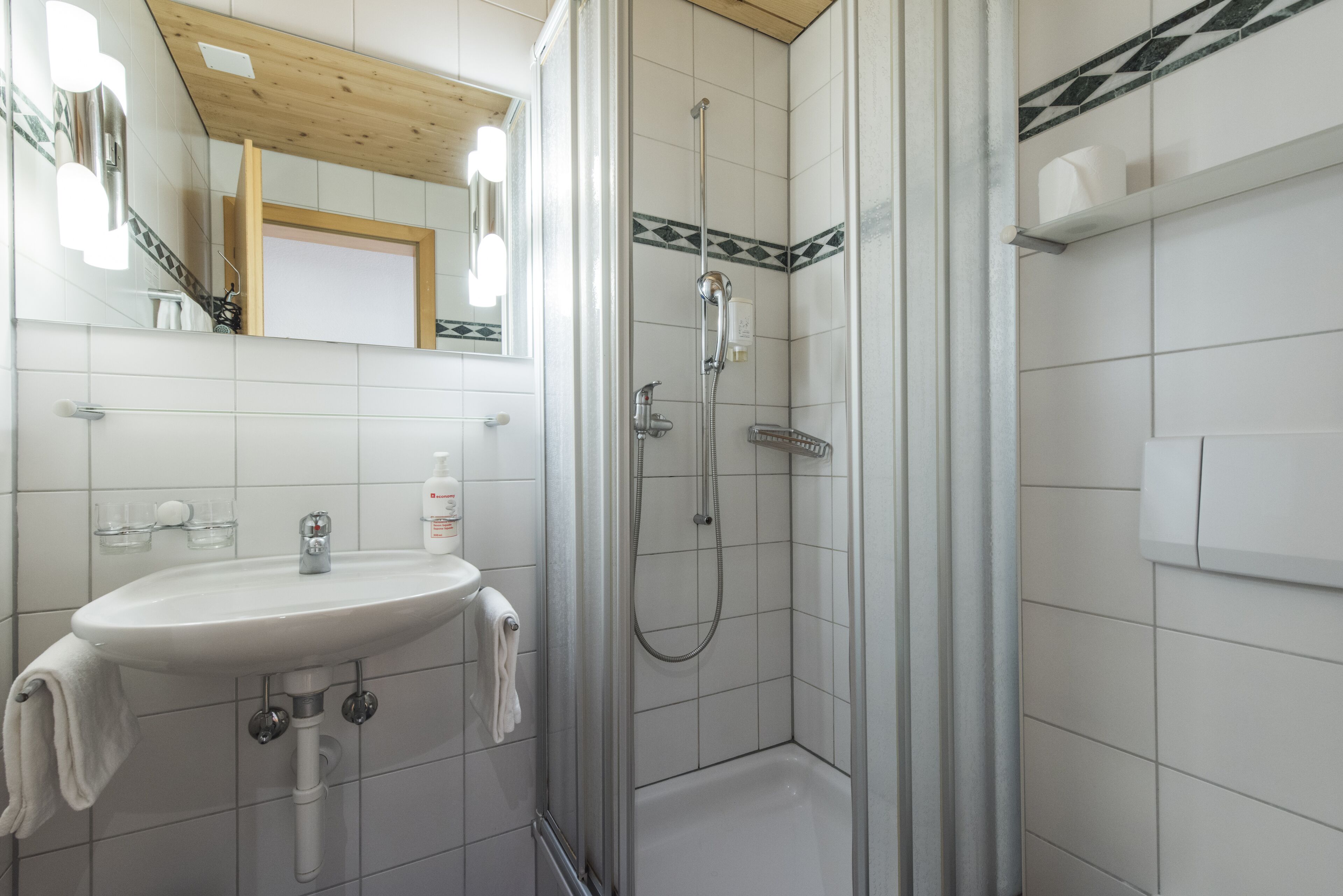 A bathroom with a white sink, mirror, and shower.