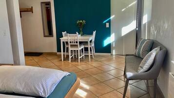 A hotel room with a bed, a seating area with a table and chairs, and a view of the outside.