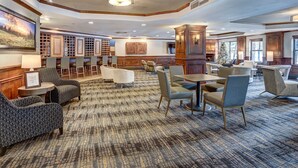 A spacious lobby with multiple seating areas, including sofas and chairs, a fireplace, and a large wall-mounted television.