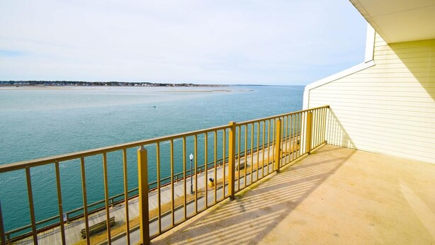 A balcony with a view of a calm sea and distant shoreline. - Crab Cove On The Bay 406 (Ocean City)