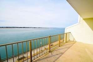 A balcony with a view of a calm sea and distant shoreline. - Crab Cove On The Bay 406 (Ocean City)