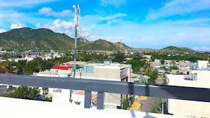 A cityscape with a prominent communication tower, buildings, and a mountainous backdrop.