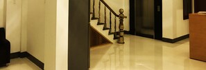 A polished hallway with a wooden staircase, a black-framed elevator, and a wooden reception desk. - Ninh Chu Hotel (Ninh Chu)