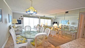 A dining area with wicker chairs and a glass table, a ceiling fan, and a chandelier. - Ocean Hideaway 503 (Ocean City)