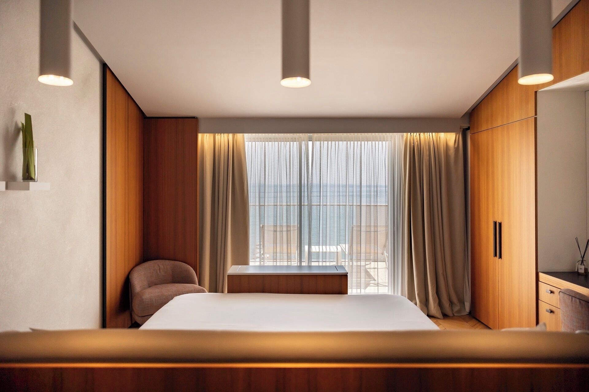 Una camera d'albergo moderna con un letto grande, un armadio in legno e vista sul mare.