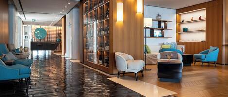 En moderne lobby med vådt gulv, reception, siddeområde og et vinudstilling.