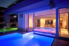 Una piscina cubierta, una piscina al aire libre, sombrillas, tumbonas