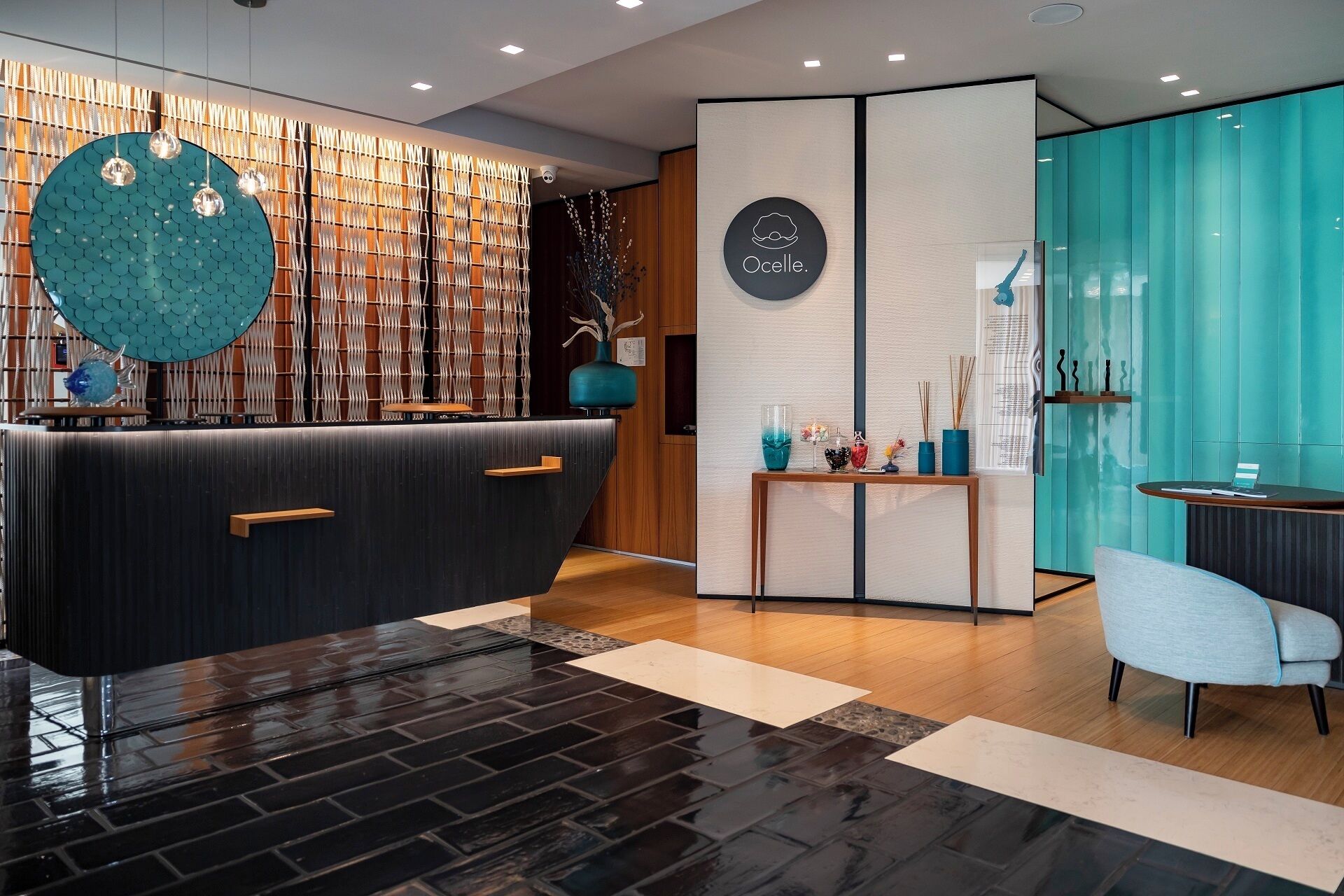 A modern reception area with a dark reception desk, a blue decorative wall, and a teal partition.
