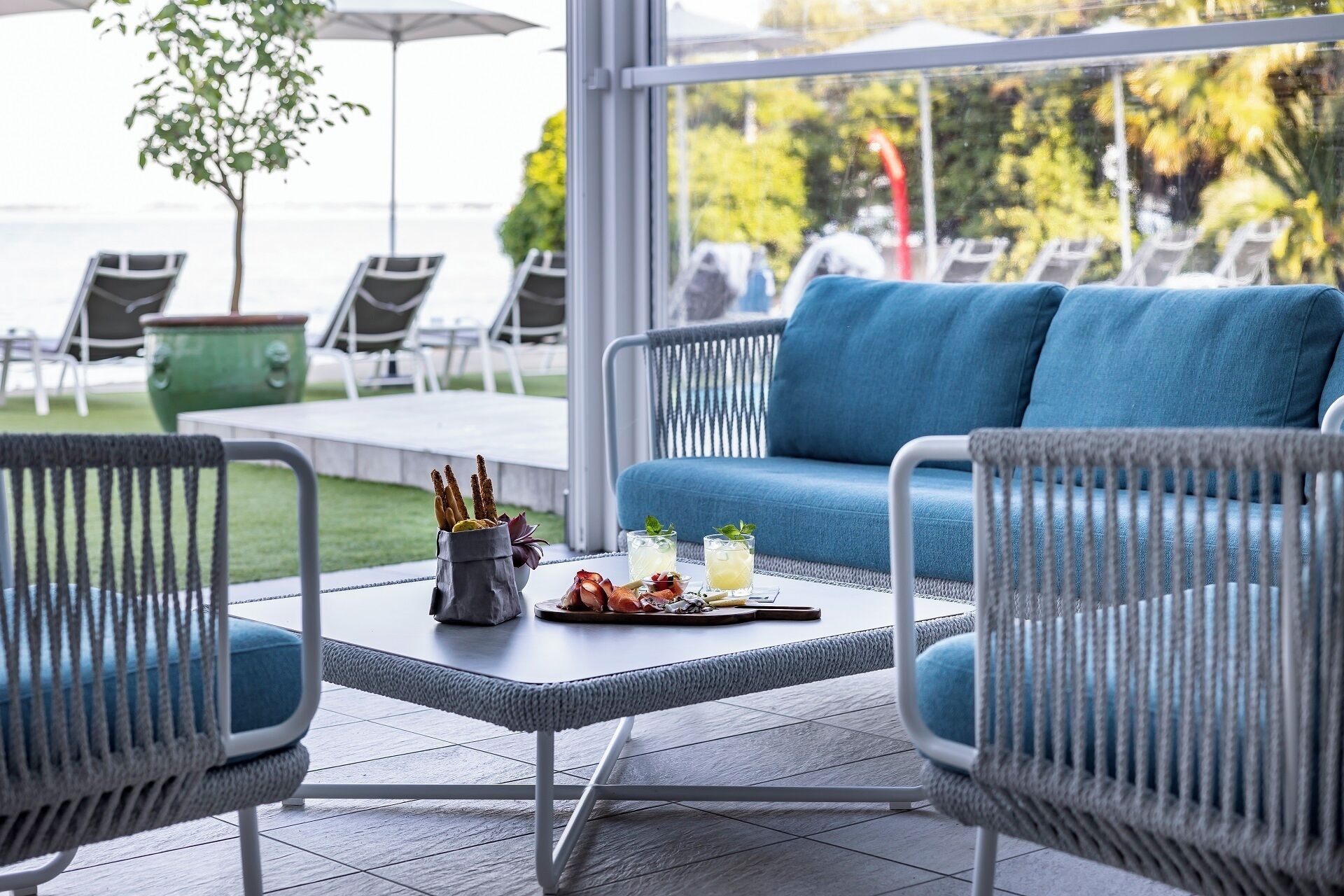 A patio area with a sofa, chairs, a table with snacks and drinks, and a view of the outdoors.
