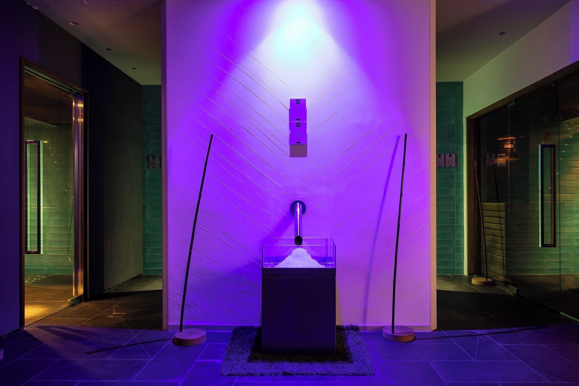 Une salle de bain moderne avec un lavabo central, un miroir et un luminaire fixé au mur.