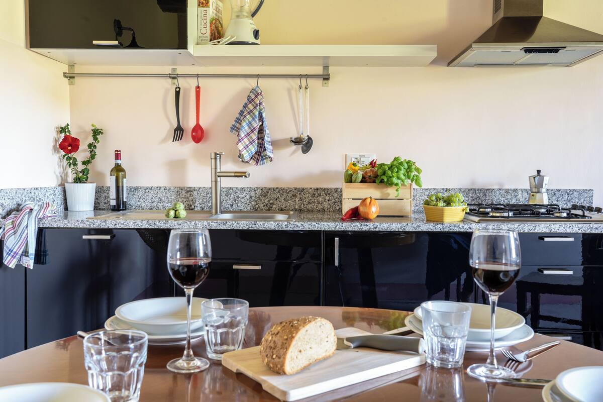 Una cocina moderna con encimeras de granito, una mesa de comedor preparada para dos personas y una variedad de utensilios y electrodomésticos.