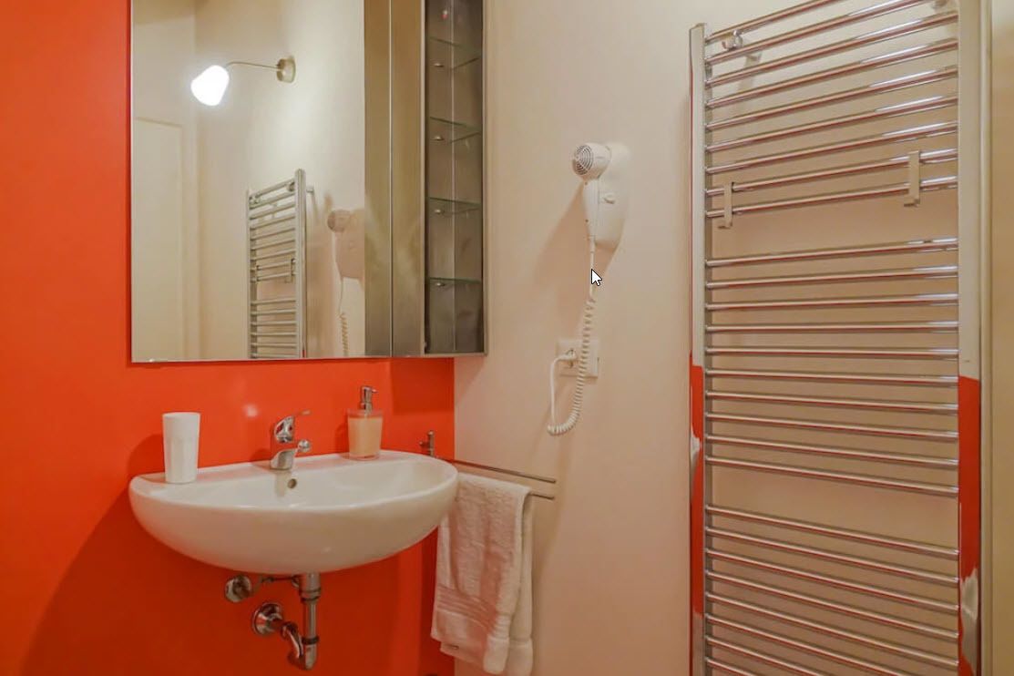 Een badkamer met een wit wastafel, een spiegel, een handdoekhouder en een haardroger.