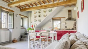 Un salon confortable avec un canapé, un coin repas avec une table et des chaises, une cuisine avec des meubles rouges et un escalier menant à un autre niveau.