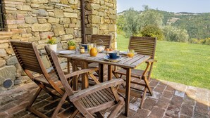 Un bâtiment en pierre avec une table et des chaises disposées pour un repas en plein air.