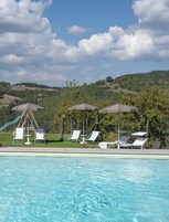 Una piscina al aire libre de temporada, sillones reclinables de piscina