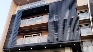 A multi-story hotel with a modern design, featuring balconies, large windows, and a well-lit entrance. - Hotel Sai Village Gurgaon (Gurugram)