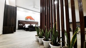 A modern hotel room with a bed, bedside tables, and potted plants. - Hotel Sai Village Gurgaon (Gurugram)