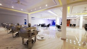 A modern hotel lobby with a marble floor, a reception area with a counter and chairs, and a dining area with tables and chairs. - Hotel Sai Village Gurgaon (Gurugram)