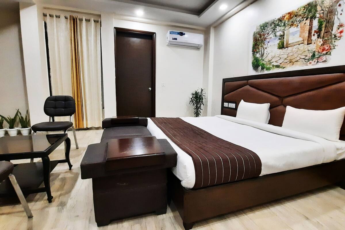 Une chambre d’hôtel avec un lit, un bureau, une chaise et une plante en pot.