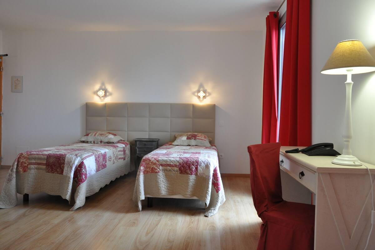 Une chambre avec deux lits, un bureau, une chaise, une lampe et un téléphone.