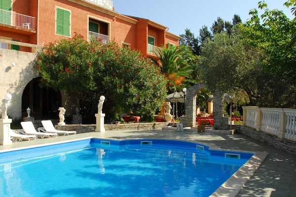 Een buitenzwembad, parasols bij het zwembad en ligstoelen