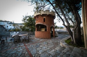 Un patio de piedra con una estructura de torre de ladrillo rústica, mobiliario exterior y un sendero de piedra.