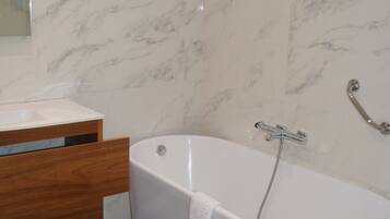 Une salle de bain avec une baignoire sur pieds, un meuble-lavabo en bois et des murs en marbre.