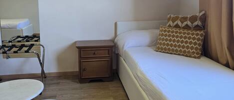 A bedroom with a bed, a nightstand, a small table, and a chair.