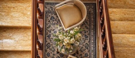Una imponente escalera con barandilla de madera, un tapete con estampado floral y dos sillones acolchados.