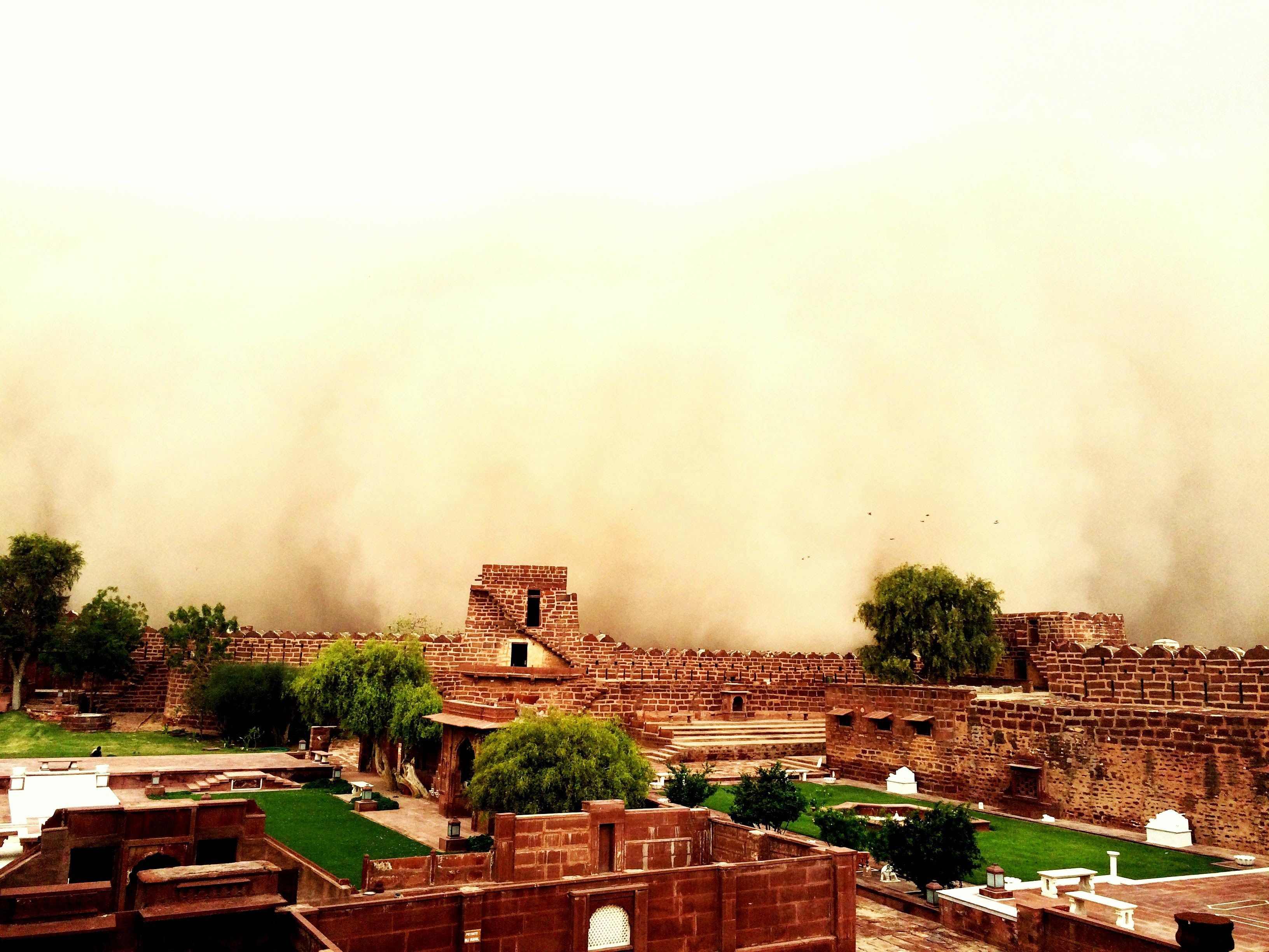 A historical fort with red brick walls and a central tower, surrounded by green lawns and trees.