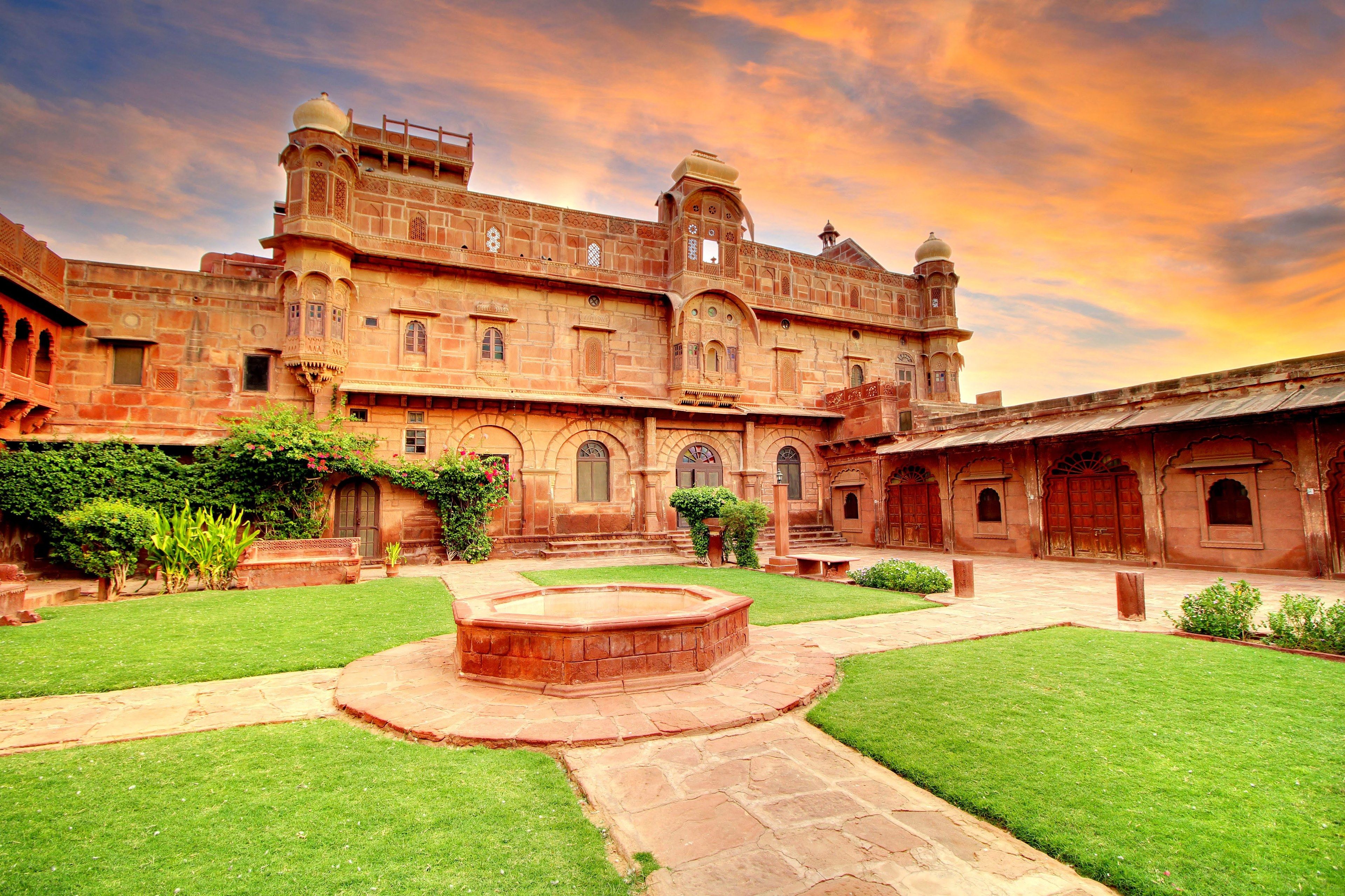 A historic building with a courtyard, arched windows, and a central water feature.