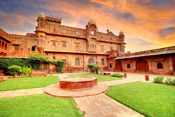 A historic building with a courtyard, arched windows, and a central water feature.