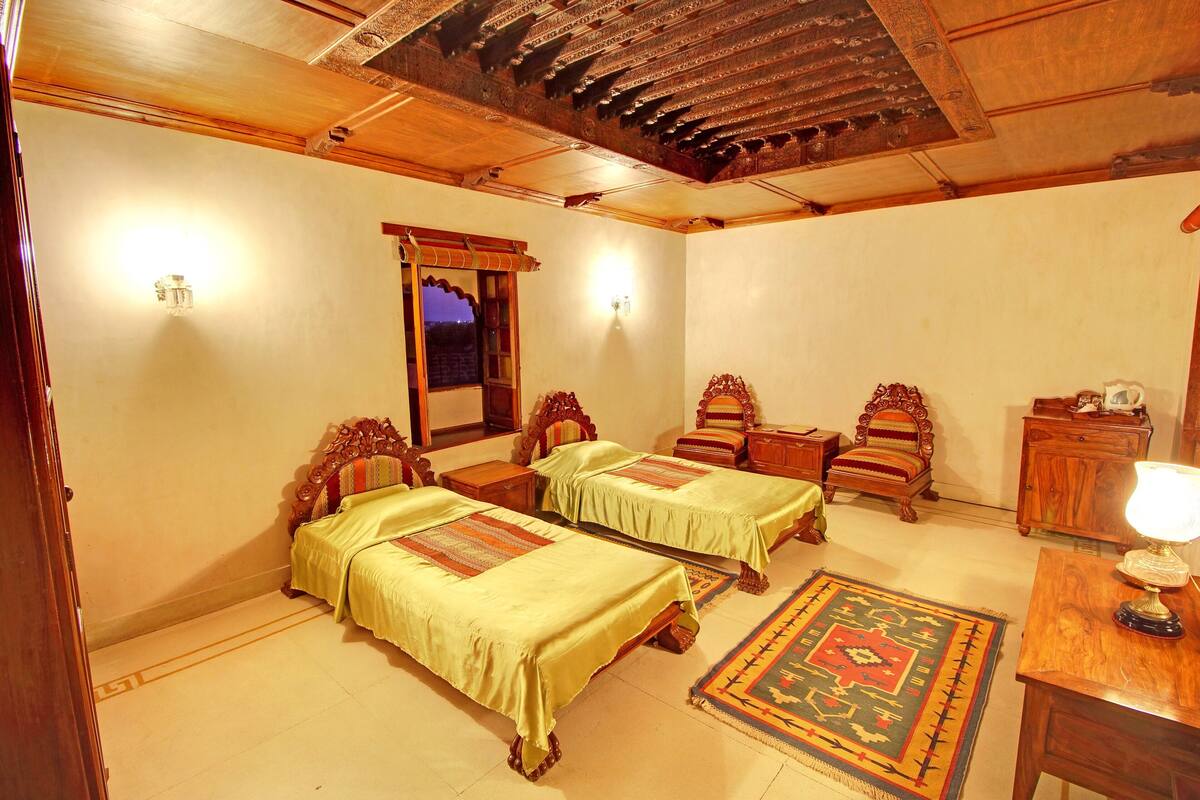 A traditional room with two wooden beds, a small wooden cabinet, and a rug.