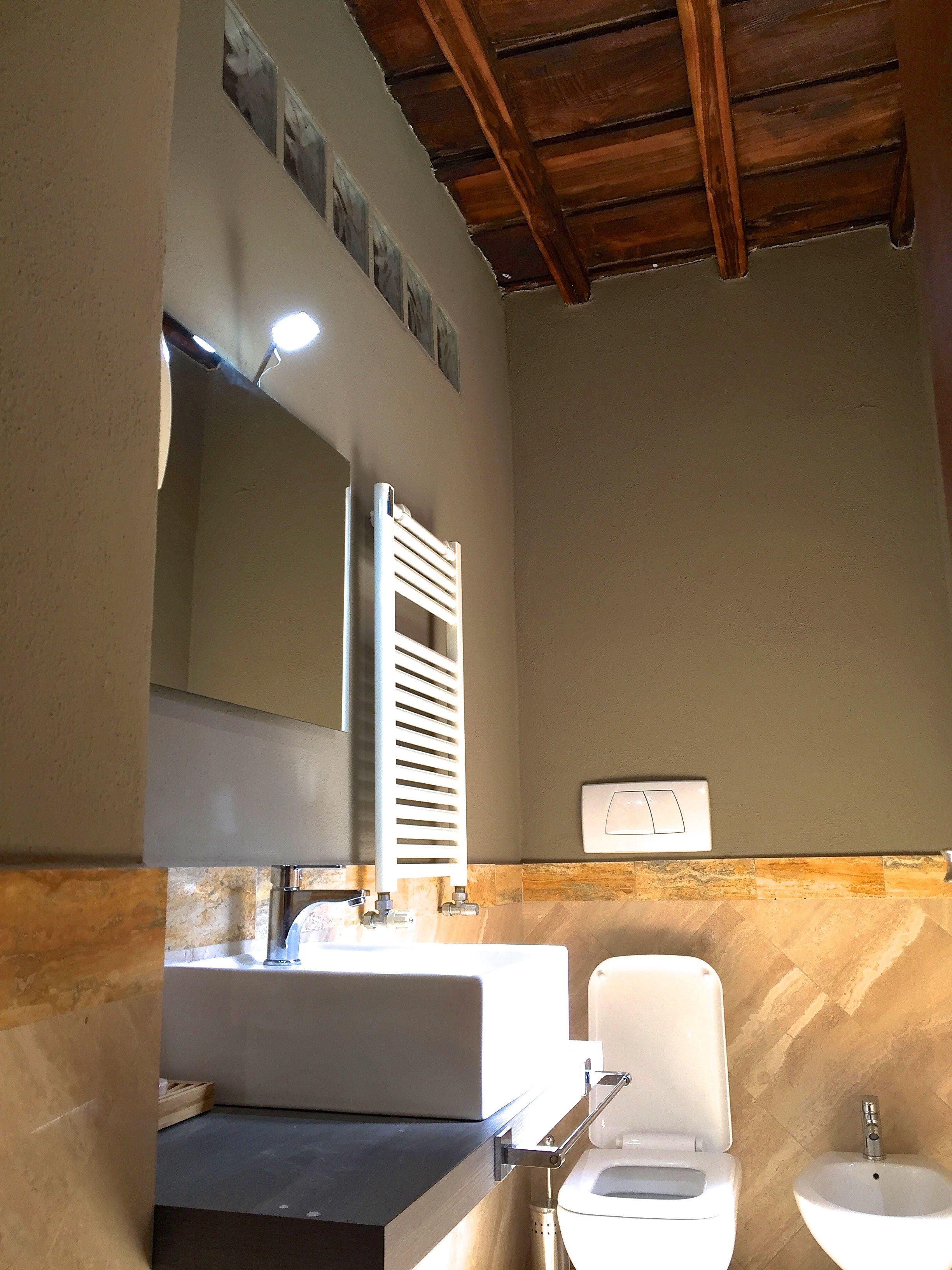 Une salle de bain avec un lavabo blanc, des toilettes et un miroir au-dessus du lavabo.