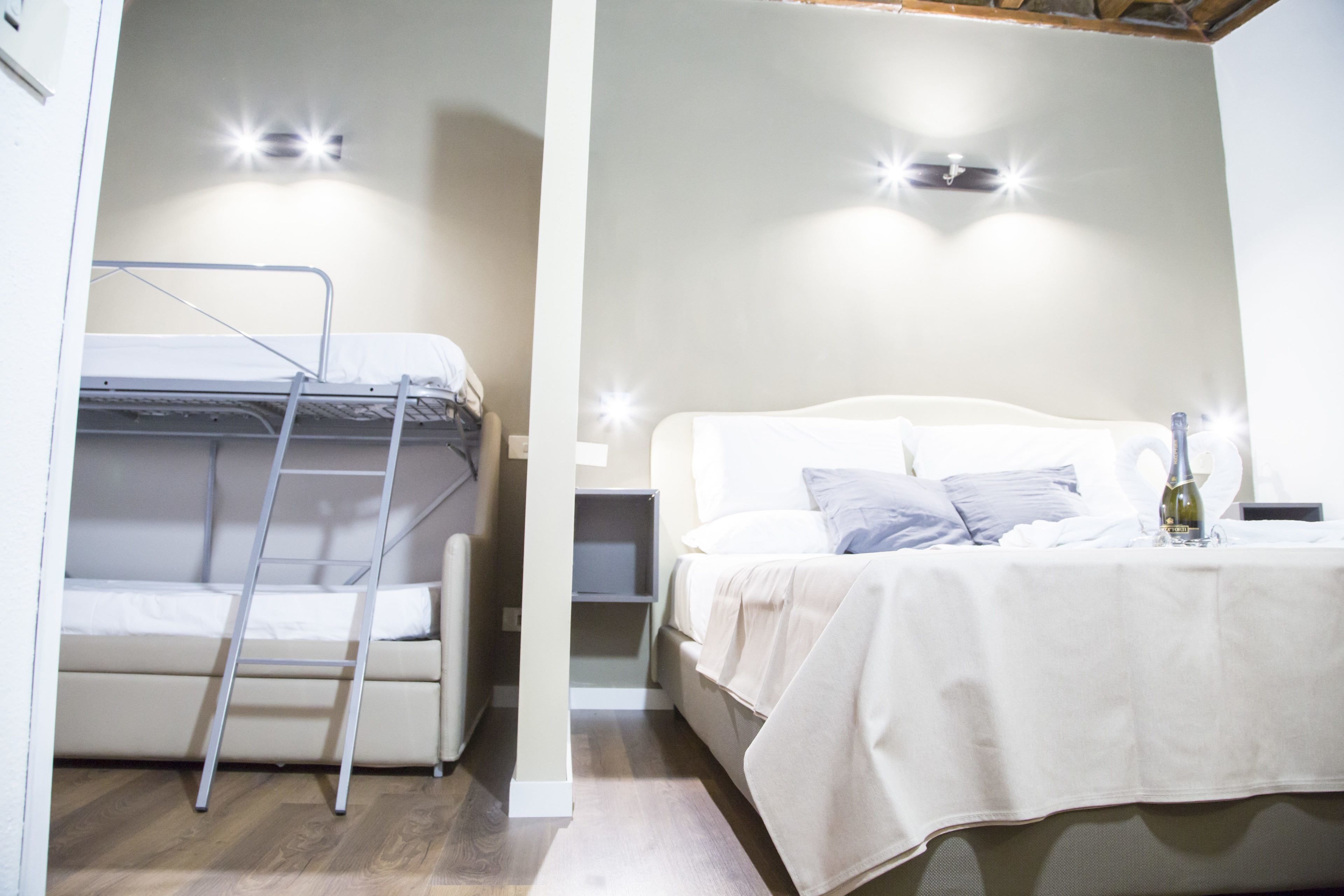 A compact bedroom with a bunk bed, a ladder, a bedside table, and a nightstand.