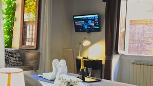 Ein Hotelzimmer mit Bett, Fernseher, einer Champagnerflasche und einer Lampe.