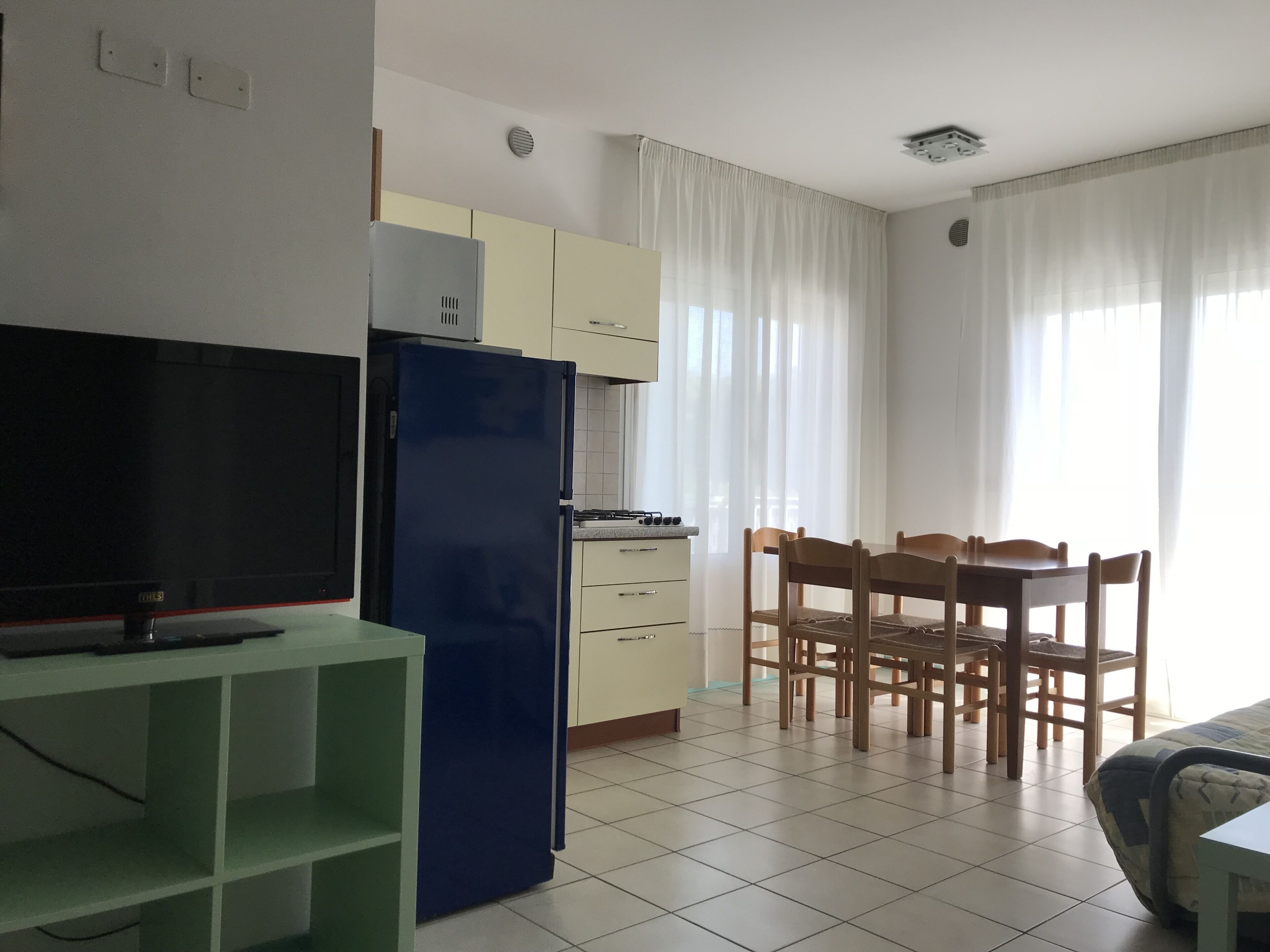 A compact kitchen with a refrigerator, a stove, and a dining table with chairs.