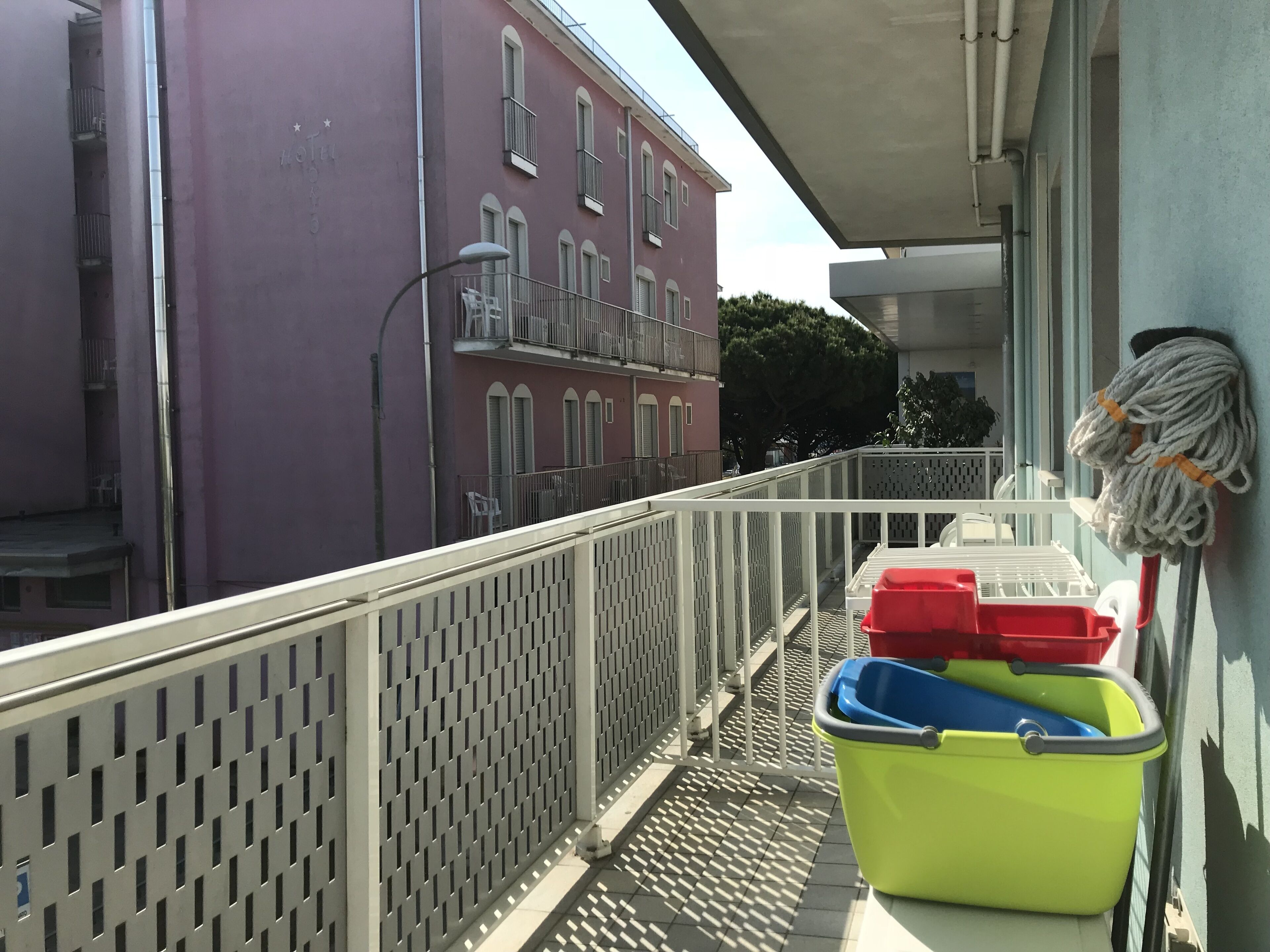 En balkon med gelænder, en moppe og rengøringsmidler.
