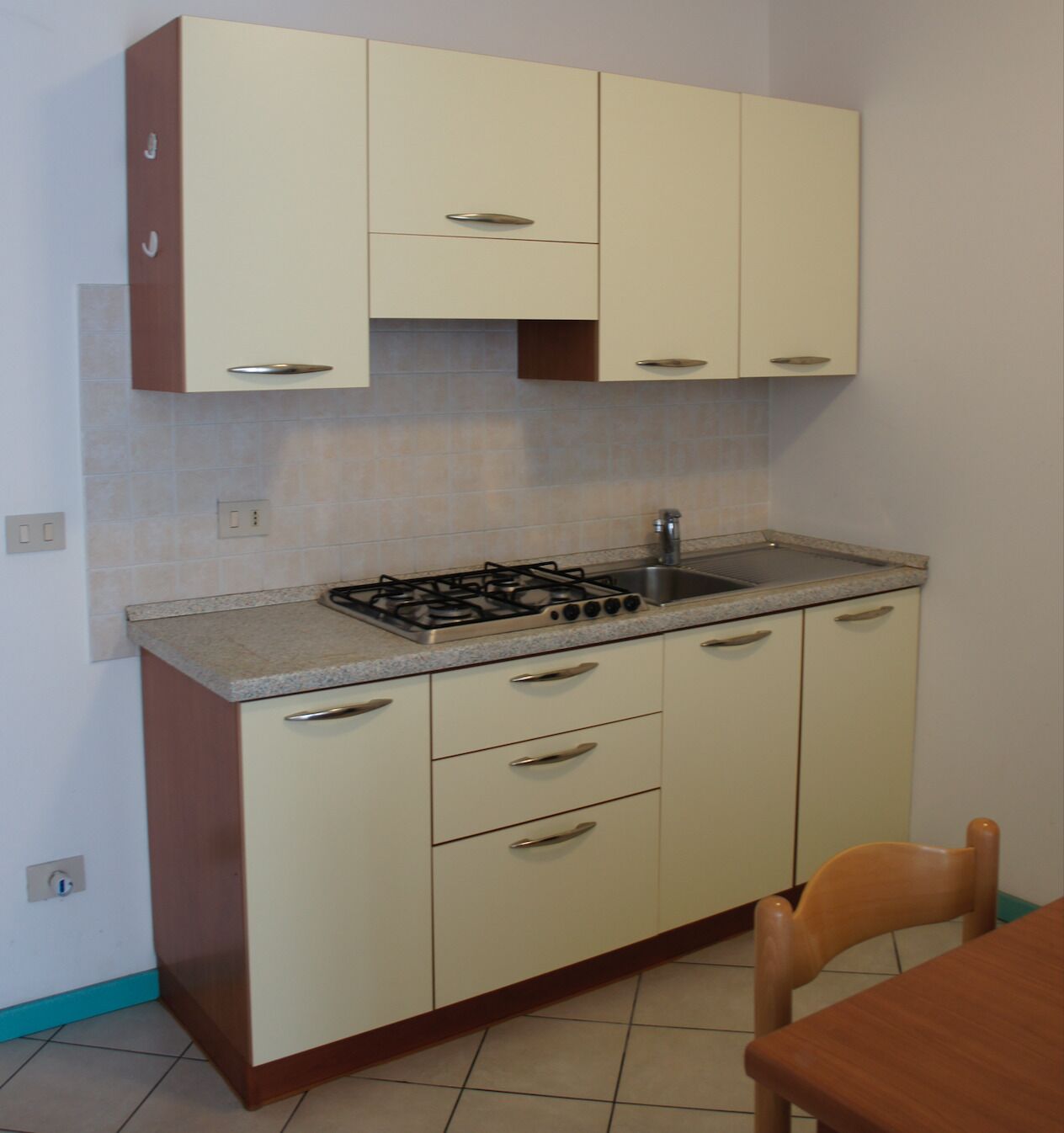 A compact kitchen with a gas stove, sink, and cabinets.