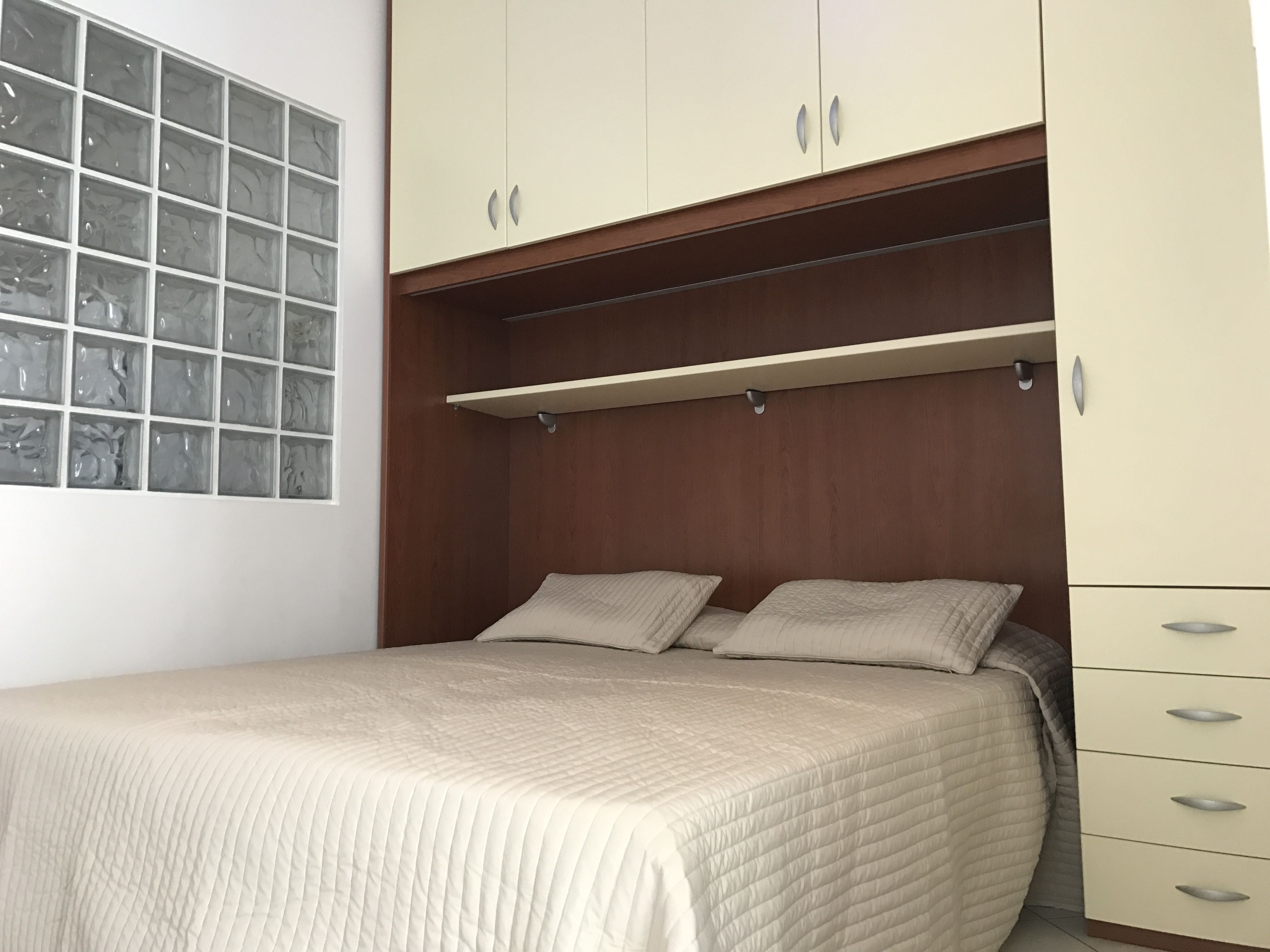A bedroom with a bed, a wardrobe, and a window with a view of trees.
