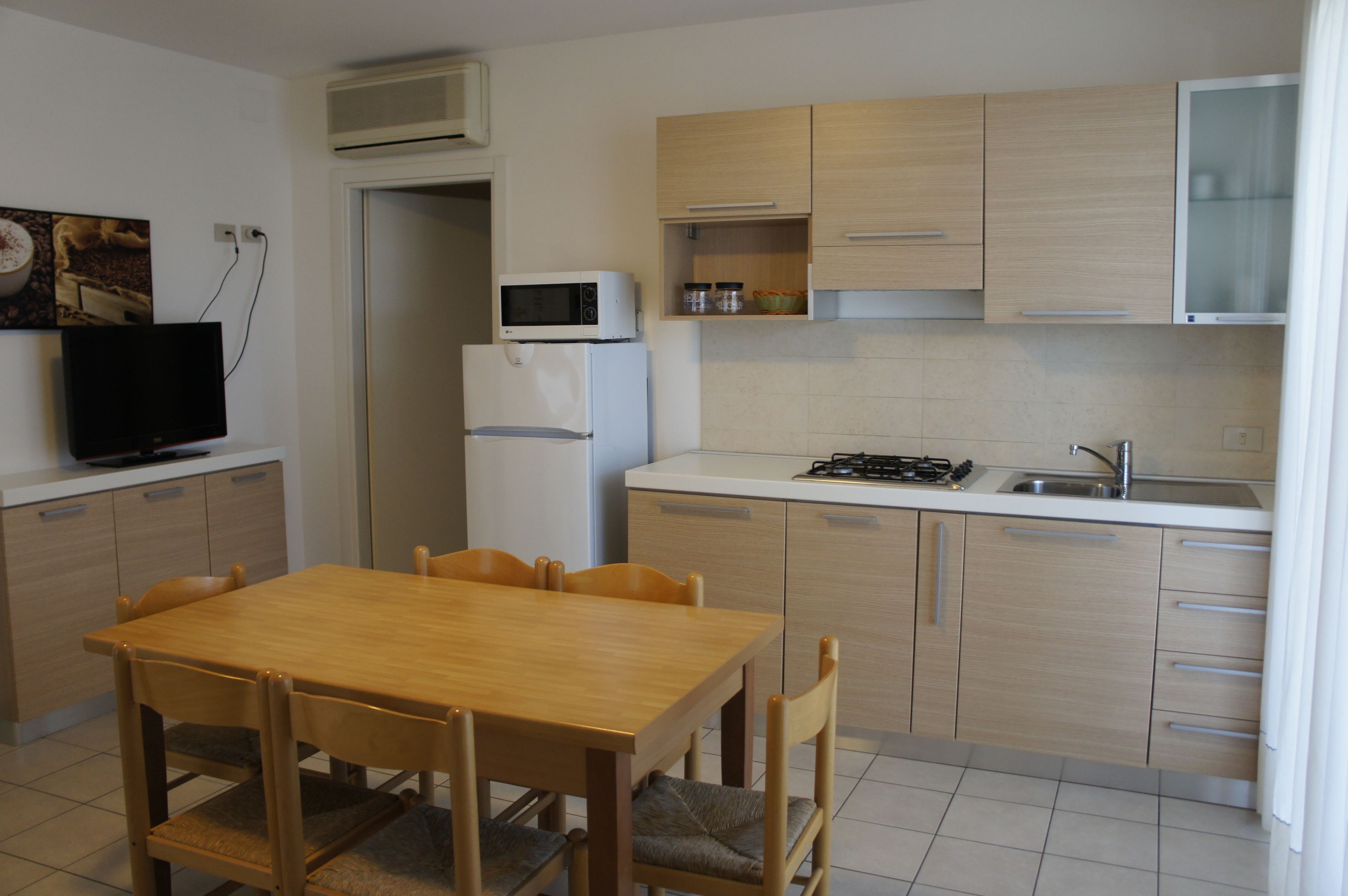 A compact kitchen with a dining table and chairs, a microwave, a refrigerator, and a stove.